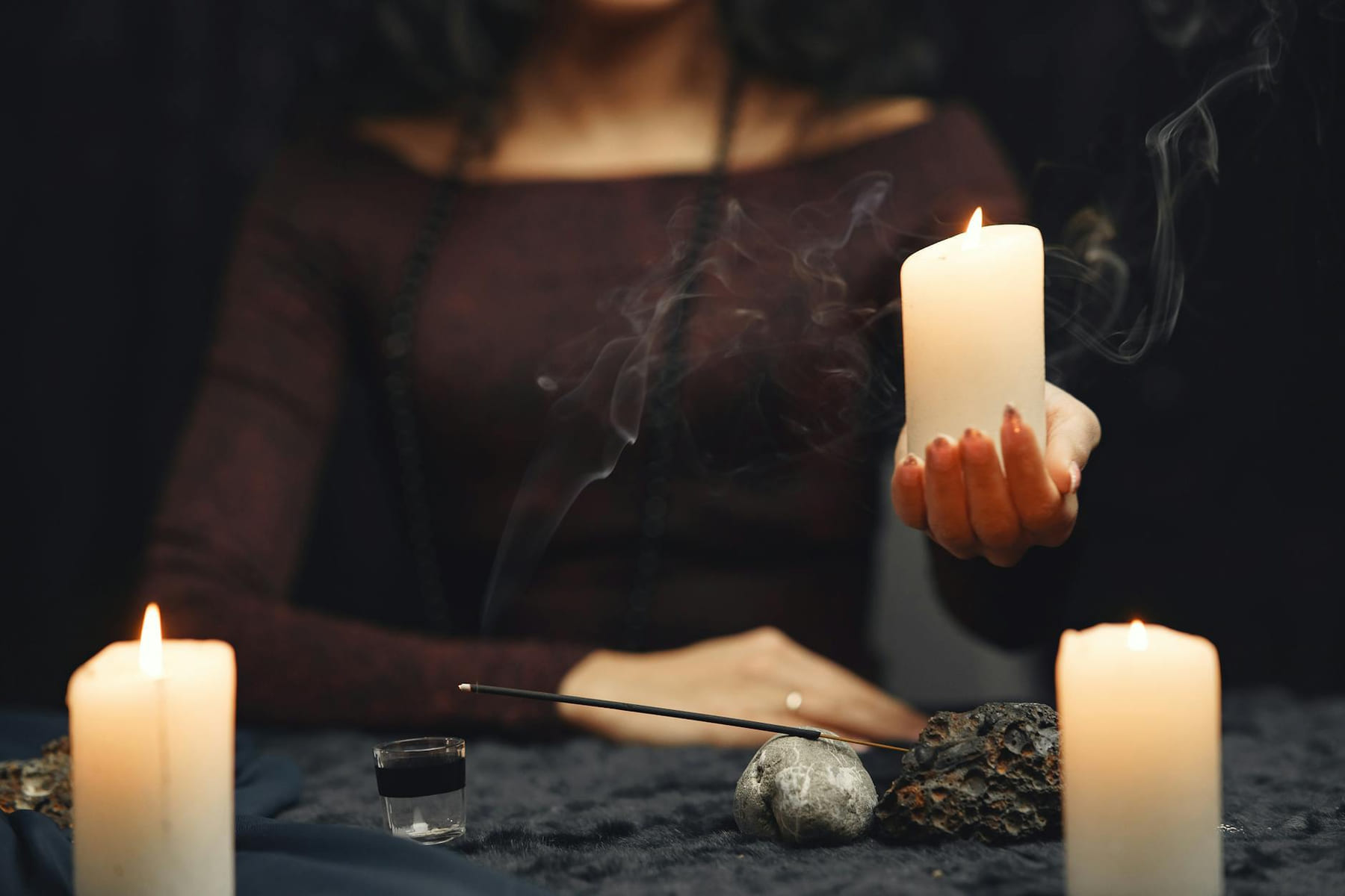 An atmospheric scene of a woman holding a lit candle during a spiritual ritual with incense and mood lighting. on The Manifesting Light