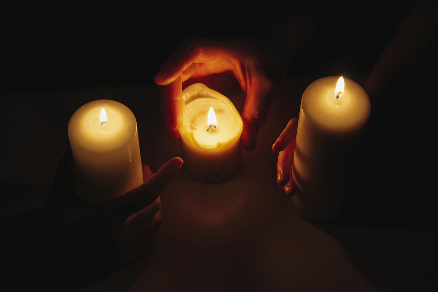 Hands holding burning candles in intimate, meditative candlelight. on The Manifesting Light