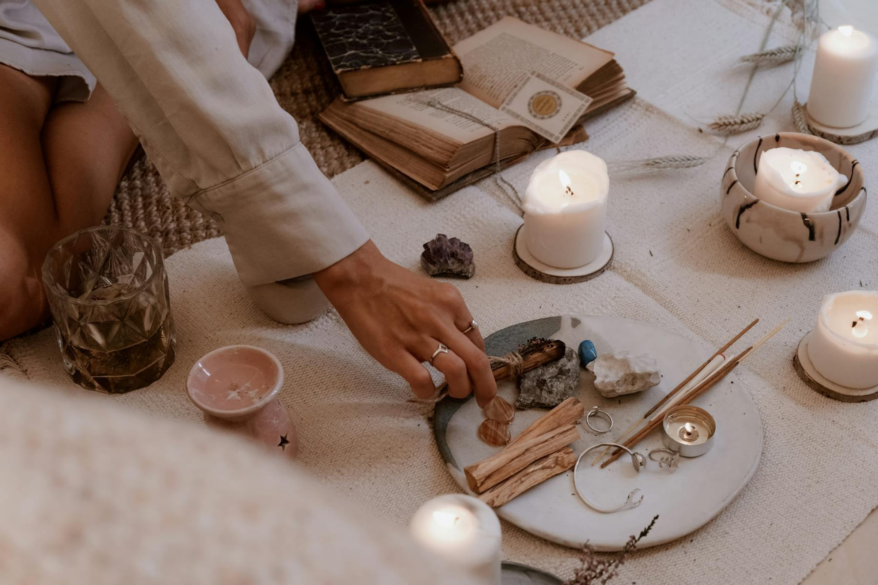 A peaceful ritual scene with candles, crystals, and incense sticks on a wooden table. on The Manifesting Light