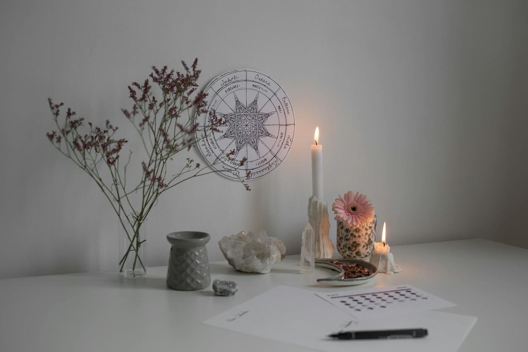 A serene desk setup with candles, crystals, and a wheel of the year decoration. on The Manifesting Light