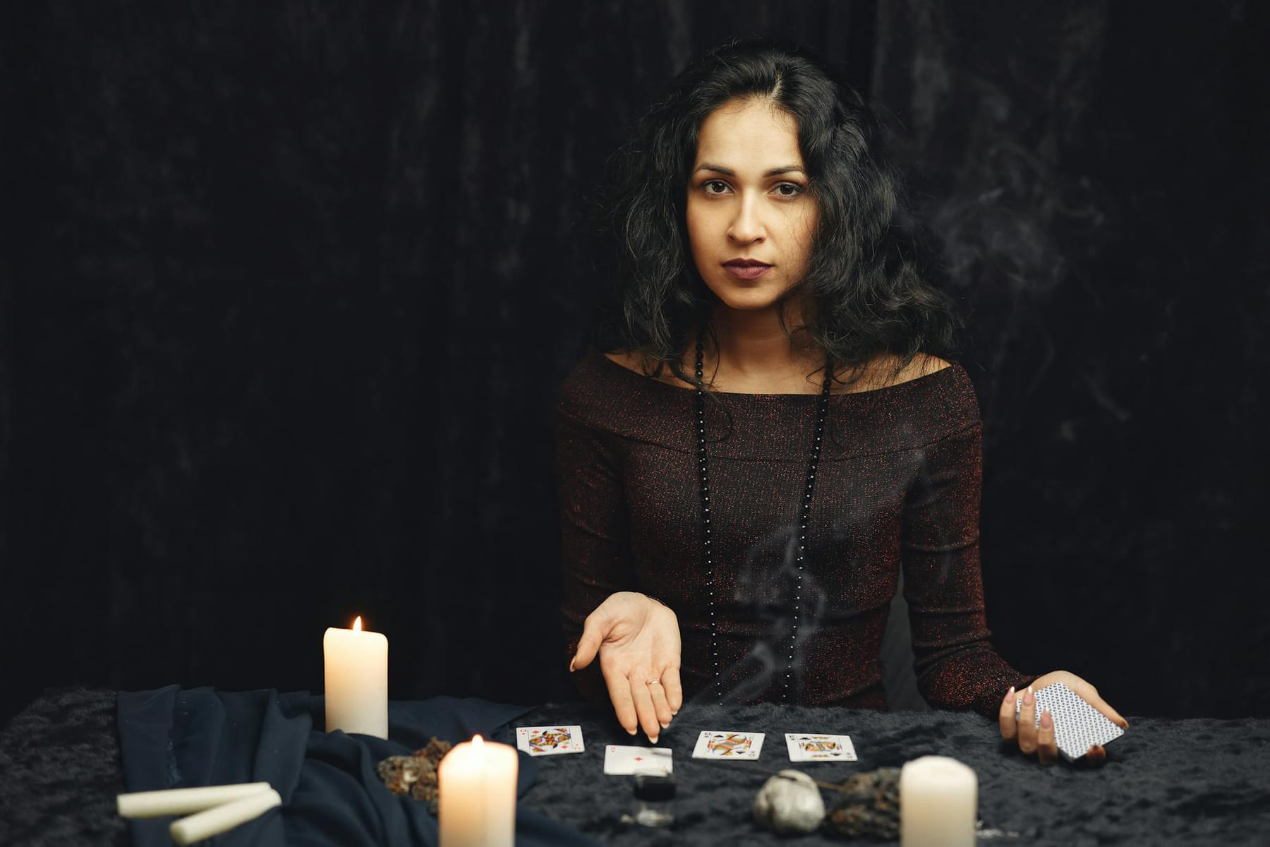 A woman engages in a tarot card reading surrounded by candles, evoking a mystical atmosphere. on The Manifesting Light