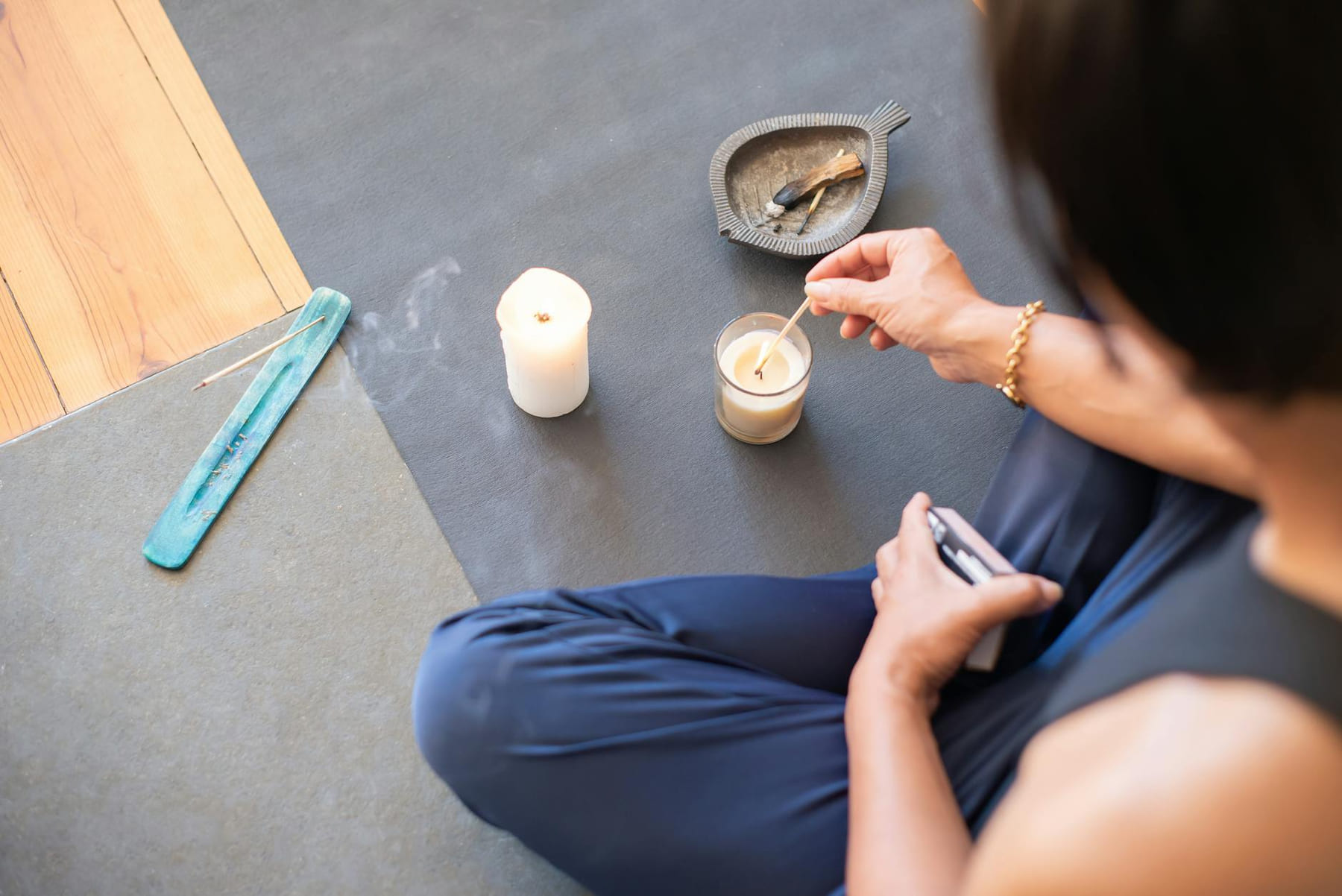 A person engages in a calming ritual with candles and palo santo, creating a serene atmosphere. on The Manifesting Light