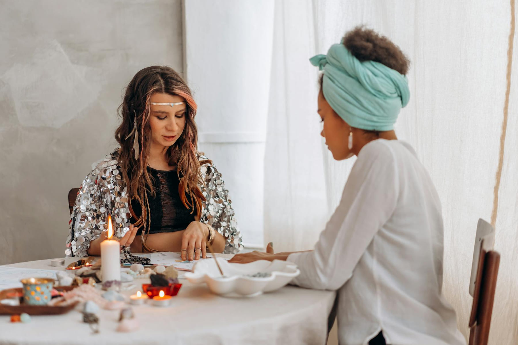 Two women engaged in a mystical fortune telling session by candlelight, indoors. on The Manifesting Light