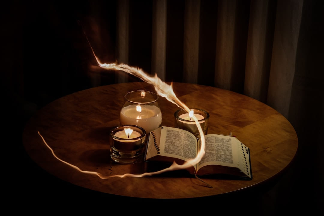 lighted candles beside book on The Manifesting Light