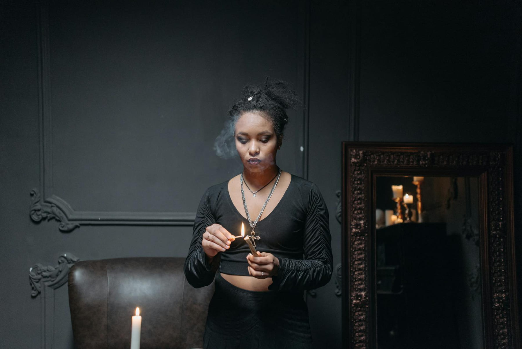 A woman engaging in a mystical ritual with a lit matchstick indoors, exuding spiritual ambiance. on The Manifesting Light