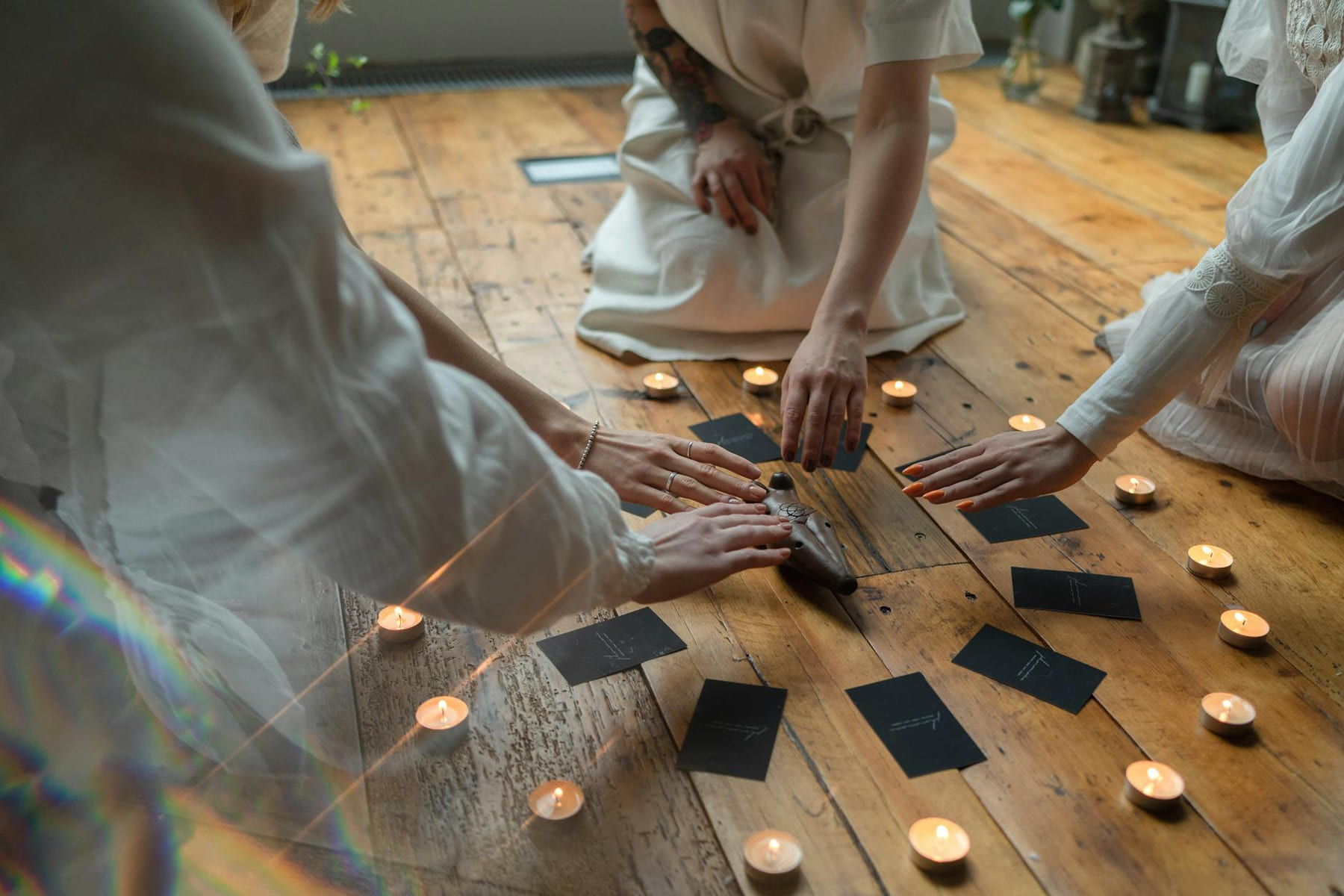 Group meditation with tarot cards and candles on a wooden floor, promoting calm and spirituality. on The Manifesting Light