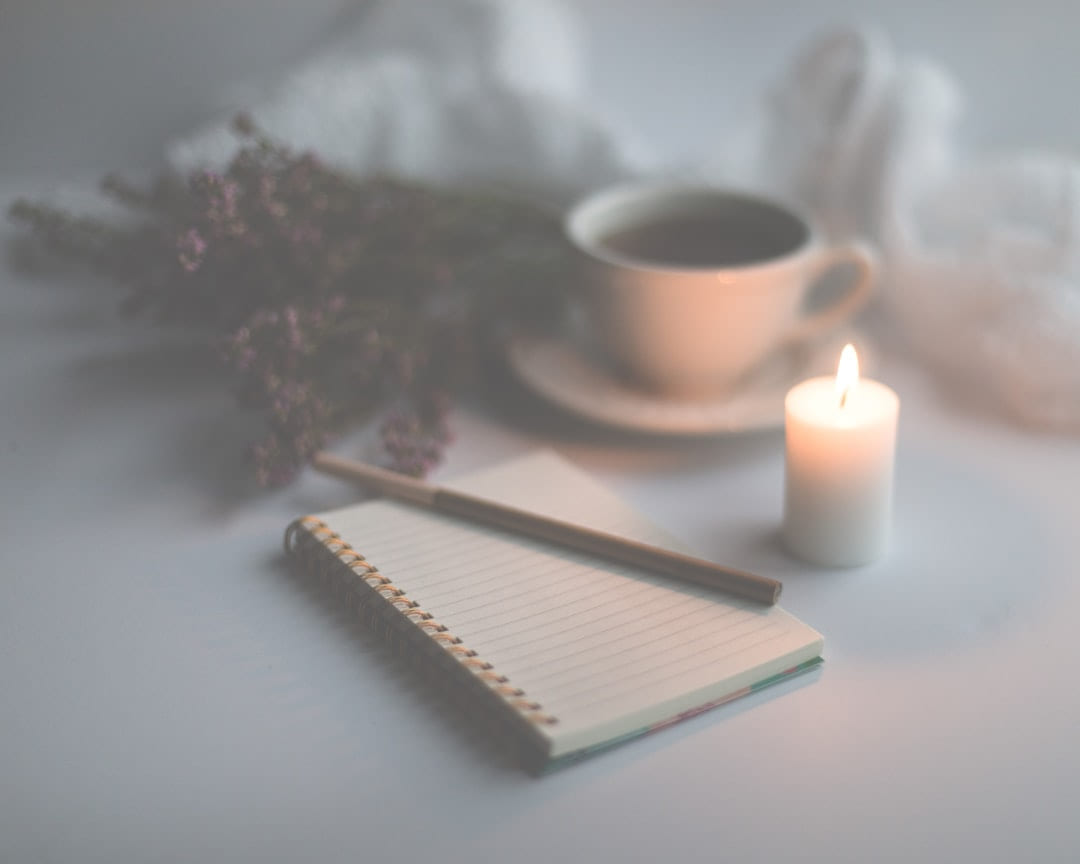 white candle on white ruled paper beside white ceramic mug on The Manifesting Light