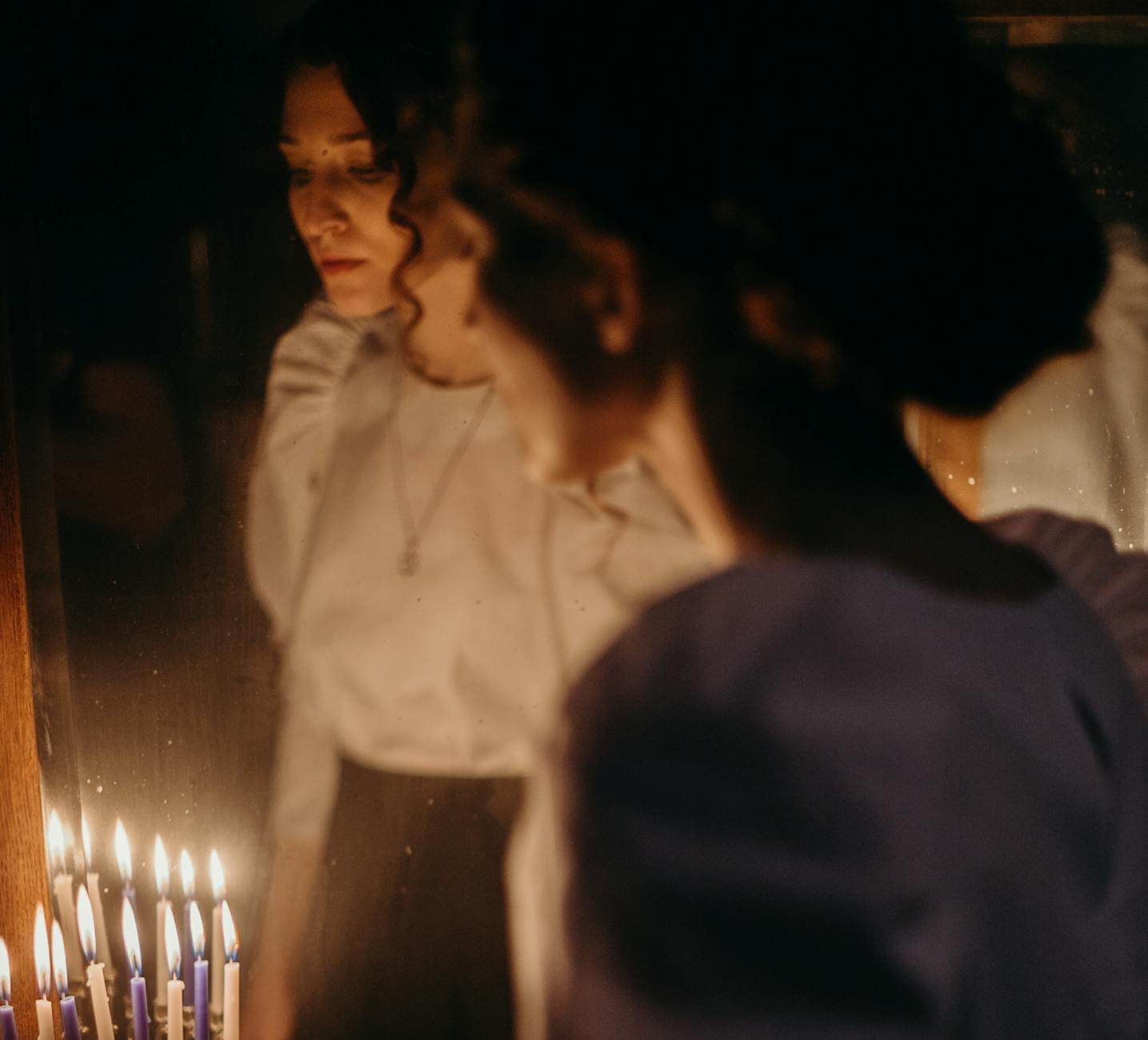 A woman reflects by candlelight, symbolizing tradition and spirituality. on The Manifesting Light