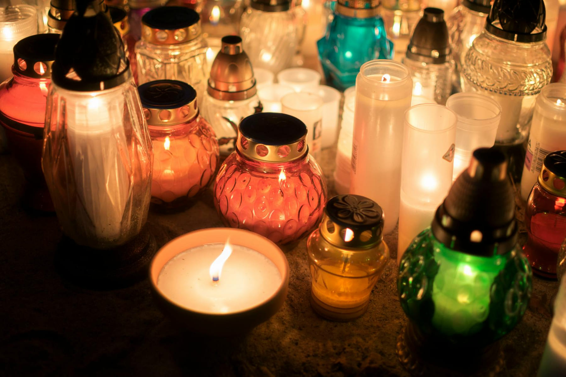 Colorful votive candles creating a warm, spiritual ambiance at an outdoor memorial. on The Manifesting Light