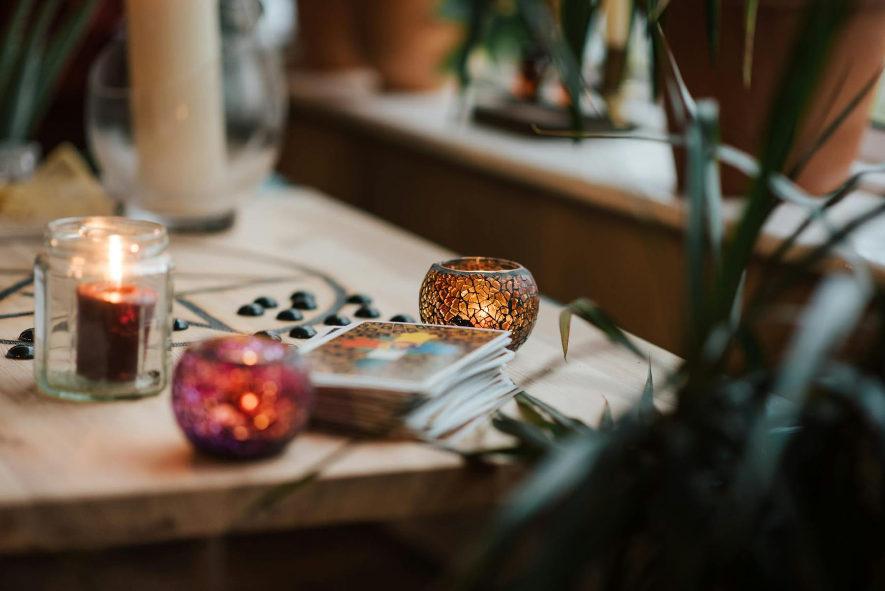Luminous candles in holders near tarot cards on table with oracle symbol at home on The Manifesting Light