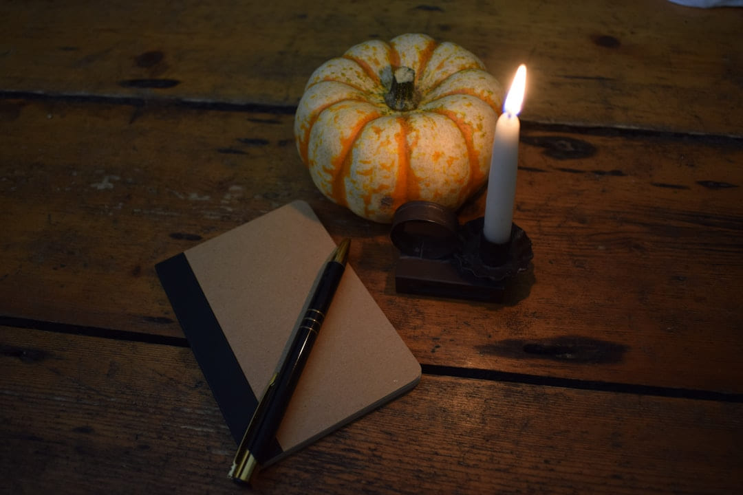 a candle and a notebook on a wooden table on The Manifesting Light